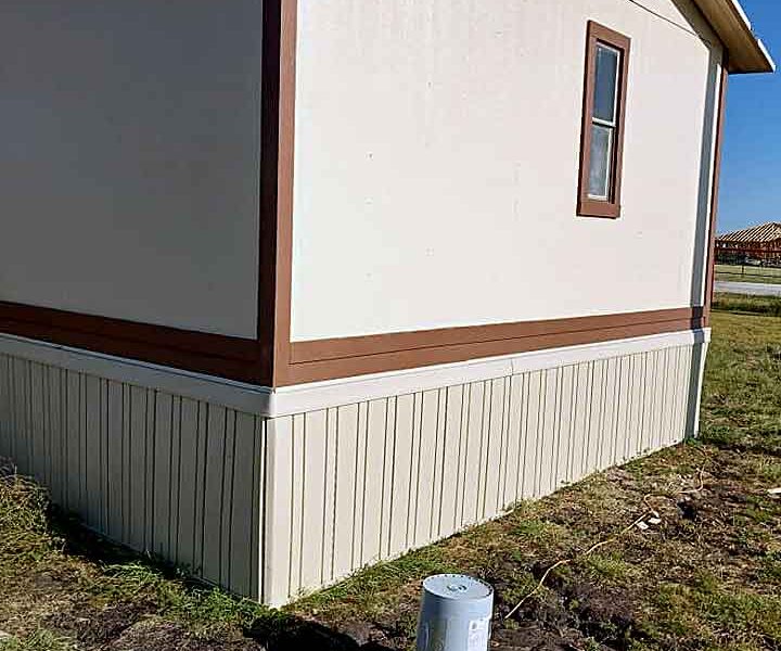 End view of a mobile home that has been leveled and new skirting installed
